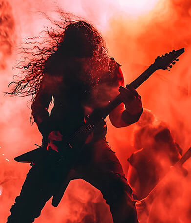 Heavy Metal Gitarrist auf einer Bühne, im Hintergrund rotes Licht im Nebel